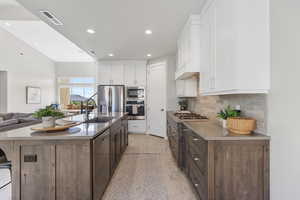 Kitchen with open floor plan, stainless steel appliances, a center island with sink, backsplash, and recessed lighting