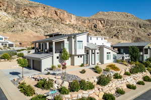 View of front of home with driveway, stucco siding, an attached garage, a mountain view, and a balcony