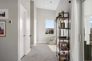 Hallway with light colored carpet and baseboards