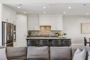 Kitchen with open floor plan, stainless steel appliances, recessed lighting, tasteful backsplash, and a kitchen island with sink