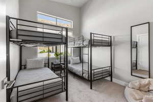 Carpeted bedroom with a towering ceiling and baseboards