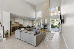 Living area with stairs, recessed lighting, a towering ceiling, and a stone fireplace