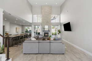 Living area featuring a stone fireplace, recessed lighting, and a high ceiling