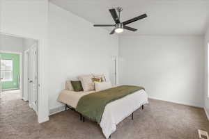 Carpeted bedroom with a ceiling fan and lofted ceiling