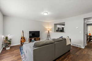 Living area featuring dark wood-style floors and a textured ceiling