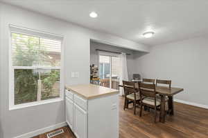 Kitchen with plenty of natural light, light countertops, white cabinetry, dark wood-style flooring, and a textured ceiling