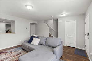 Living room featuring dark wood-style floors, a textured ceiling, and stairs