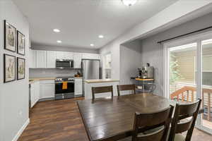 Kitchen featuring light countertops, appliances with stainless steel finishes, white cabinets, dark wood finished floors, and recessed lighting