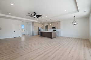 Kitchen with open floor plan, light countertops, pendant lighting, a center island with sink, and recessed lighting