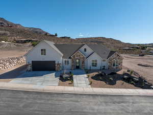 Modern farmhouse with a mountain view, stone siding, driveway, a garage, and stucco siding