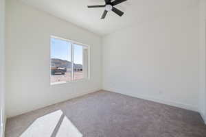 Spare room featuring carpet flooring, a mountain view, and a ceiling fan