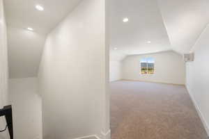 Additional living space with lofted ceiling, light colored carpet, and recessed lighting
