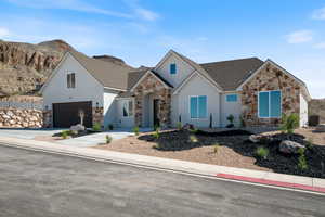 View of front of house featuring stone siding, a shingled roof, stucco siding, and concrete driveway