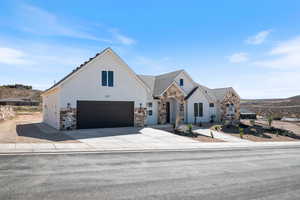 View of front of property with stone siding, driveway, stucco siding, and a garage