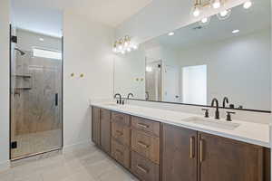 Bathroom with a stall shower, double vanity, light tile patterned floors, and recessed lighting