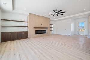 Unfurnished living room with light wood finished floors, a fireplace, recessed lighting, ceiling fan, and arched walkways