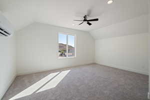 Additional living space with vaulted ceiling, carpet, a wall unit AC, a mountain view, and recessed lighting