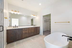 Bathroom featuring double vanity, a freestanding tub, recessed lighting, a shower stall, and a walk in closet