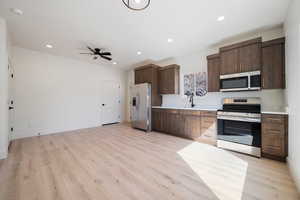 Kitchen with light countertops, stainless steel appliances, dark brown cabinetry, recessed lighting, and light wood-type flooring