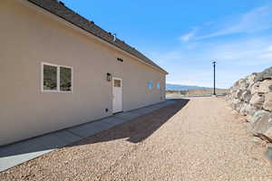 View of property exterior with stucco siding, roof with shingles, and a mountain view