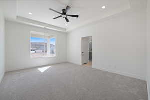 Unfurnished room with a raised ceiling, light carpet, ceiling fan, and recessed lighting