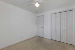 Unfurnished bedroom with light colored carpet, a ceiling fan, and a closet