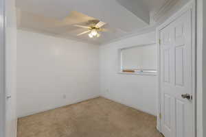 Spare room with ornamental molding, light colored carpet, and a ceiling fan