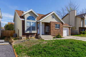 View of front facade with brick siding, an attached garage, and roof with shingles
