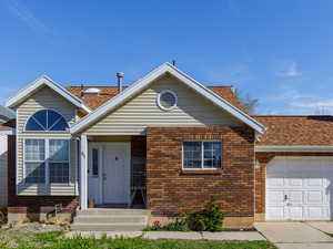 View of front of property featuring brick siding, a garage, concrete driveway, and a shingled roof