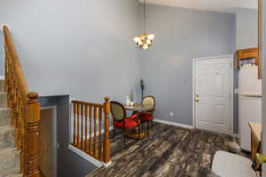 Foyer featuring high vaulted ceiling, dark wood-style floors, stairs, and a chandelier