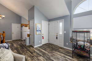 Entrance foyer featuring high vaulted ceiling, dark wood-style flooring, and stairway