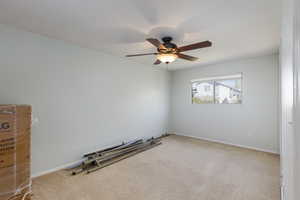 Carpeted spare room featuring baseboards and ceiling fan