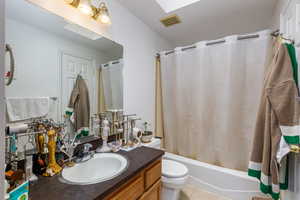 Full bathroom with shower / bath combo with shower curtain, vanity, light tile patterned flooring, and a skylight