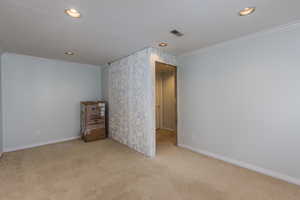 Empty room featuring light colored carpet, ornamental molding, and recessed lighting