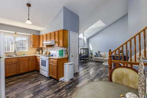 Kitchen with brown cabinetry, light countertops, pendant lighting, white appliances, and decorative backsplash