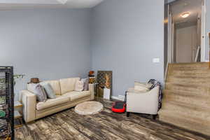 Living room with dark wood-type flooring and stairs