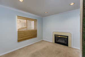 Unfurnished living room with crown molding, a glass covered fireplace, carpet, and recessed lighting