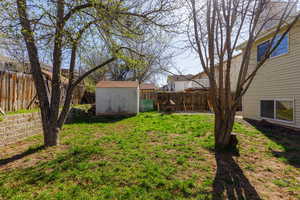 Fenced backyard featuring a shed