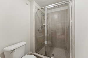 Bathroom with a shower stall and toilet