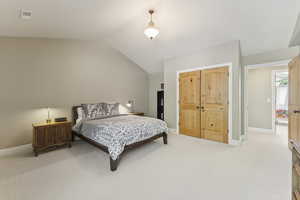 Bedroom featuring carpet flooring, lofted ceiling, and a closet