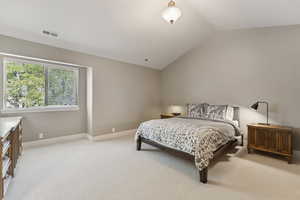 Bedroom featuring light carpet and lofted ceiling