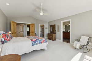 Bedroom featuring lofted ceiling, carpet, a ceiling fan, connected bathroom, and a spacious closet