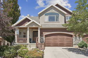 Craftsman inspired home featuring covered porch, a garage, concrete driveway, roof with shingles, and stone siding