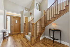 Entrance foyer featuring stairs, light wood finished floors, and a high ceiling