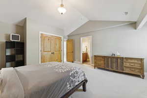 Bedroom with a closet, carpet, lofted ceiling, and ensuite bath