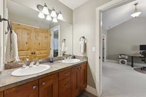 Full bath featuring double vanity and lofted ceiling