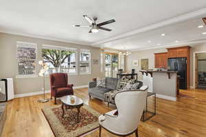 Living room with crown molding, light wood-type flooring, a chandelier, recessed lighting, and a ceiling fan