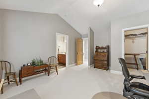 Carpeted office space featuring vaulted ceiling and baseboards