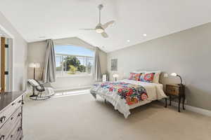 Bedroom with vaulted ceiling, light colored carpet, and a ceiling fan
