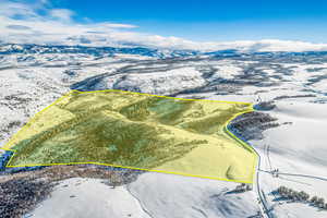 Snowy aerial view featuring property parcel outlined and a mountain view